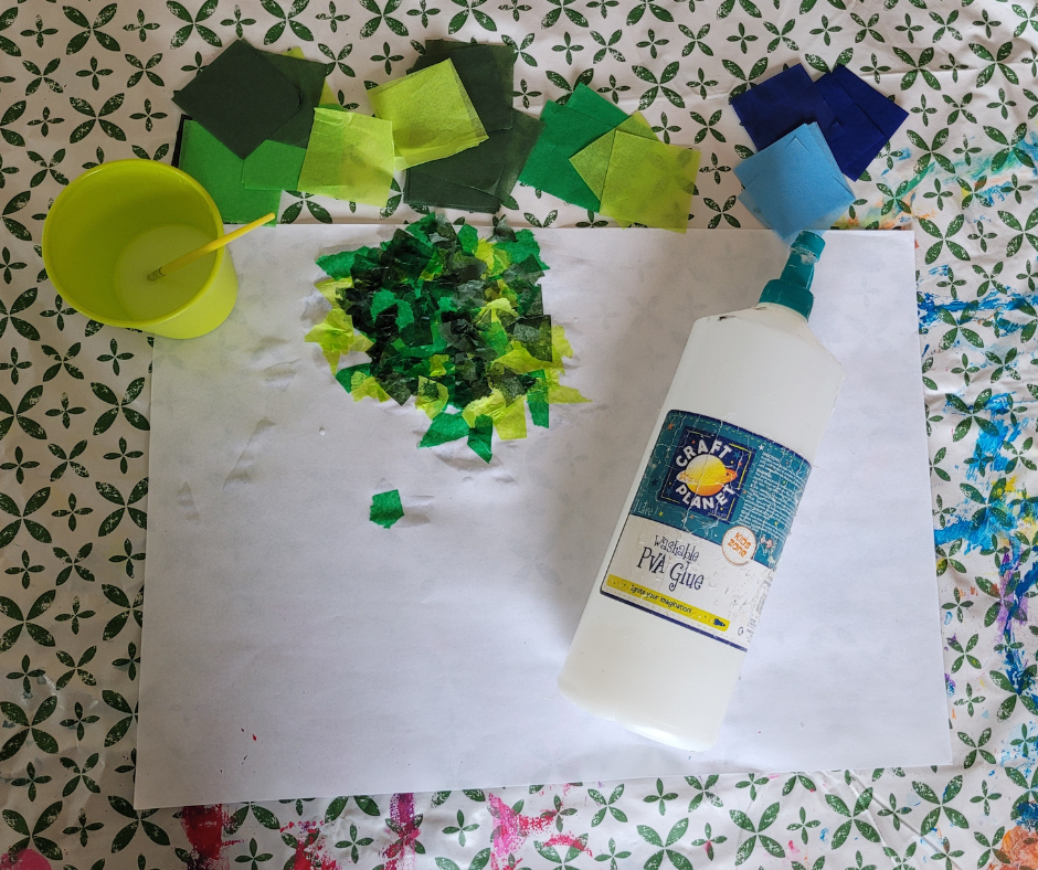 An image of pva glue, a pot with pva glue and water mixed together, a paintbrush,  colored tissue paper in greens and blues, and a big sheet of white paper that has pieces of ripped up tissue paper stuck to it to make a collage.
